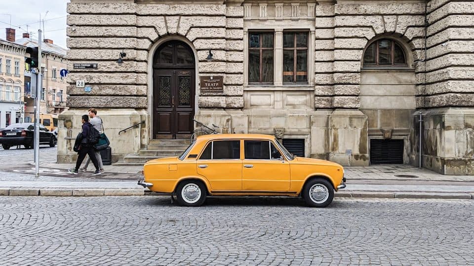yellow sedan parked beside concrete building