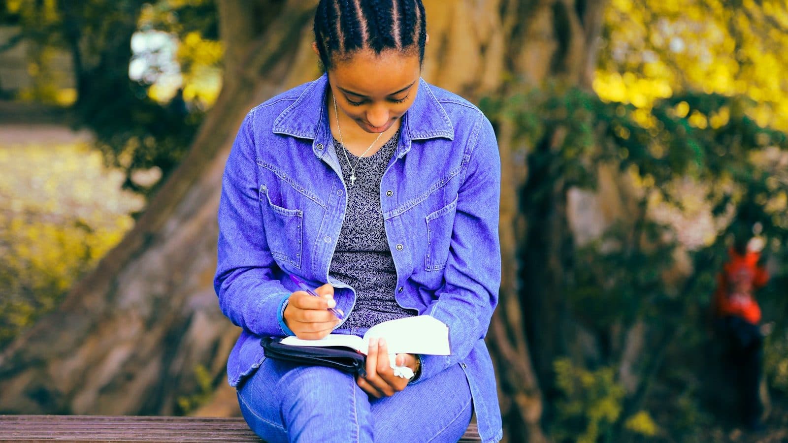 selective focus photography of woman reading book while sitting at bench