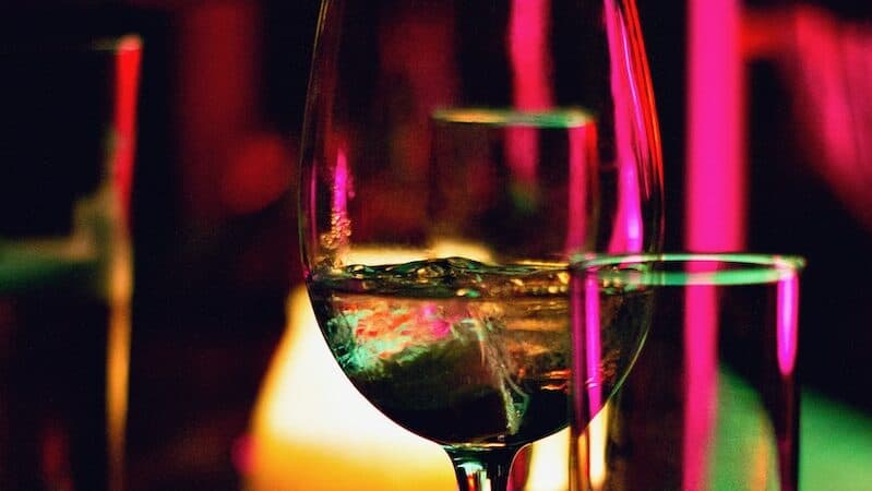 half filled wine glass beside half empty clear pint glass