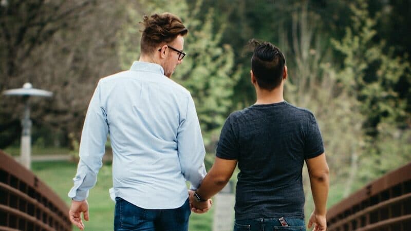 man in white long sleeve shirt and blue denim jeans holding hands with woman in blue
